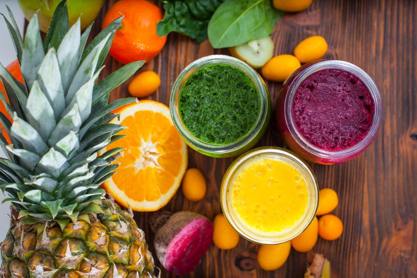 a green, a purple, and an orange jar next to each other with fruit